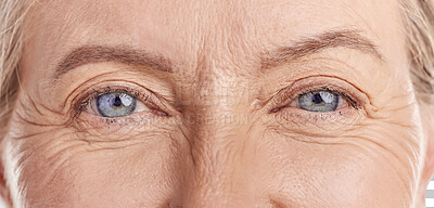 Closeup portrait of a beautiful older woman's blue eyes. Healthy and natural mature woman with deep lines and crows feet, Feeling radiant and fresh while doing her daily beauty routine in a studio