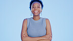 Portrait, laughing a black woman arms crossed on a blue background while standing in studio. Face, motivation and funny with an attractive female feeling positive or confident on a color wall