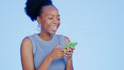 Buy stock photo Cellphone, happy and black woman in a studio networking on social media, mobile app or the internet. Smile, technology and young African female model scroll on a phone isolated by blue background.