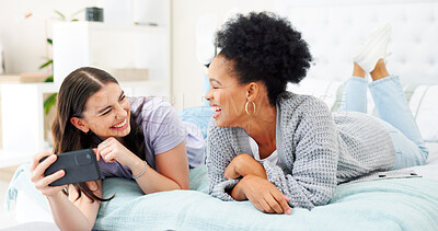 Buy stock photo Phone, social media and woman friends laughing on bed together while looking at an internet meme. Smile, diversity and comedy with funny young people joking in the bedroom of a home in the morning