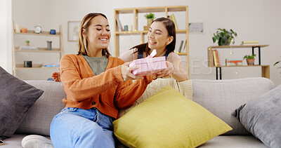 Buy stock photo LGBT, love and lesbian couple with surprise gift on a sofa for birthday, anniversary or gesture in their home. Homosexual, marriage and women with box present in a living room with romance and care