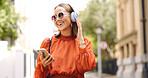 Phone, music and woman dance in a city with headphones, happy and good mood outdoors. Radio, street and asian female dancing to podcast , excited and cheerful, free or positive in London