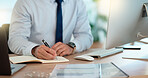 Lawyer and attorney working on corporate plans and compiling legal reports for a case at his desk. Business man and project manager writing notes on paper while working on a computer in an office