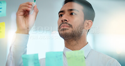 Buy stock photo Project manager planning a strategy while writing notes on a glass wall in an office. Businessman brainstorming and thinking of ideas for his presentation. Serious male entrepreneur being innovative