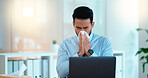 A modern business man feeling sick with covid fatigue while working online at a desk on his laptop. Closeup of an male corporate manager blowing his nose. An ill office worker frustrated at work.