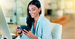 Happy woman making online payment with phone and bank card for typing credit details into online banking app. Young business woman enjoying virtual shopping or wireless purchase while sitting inside