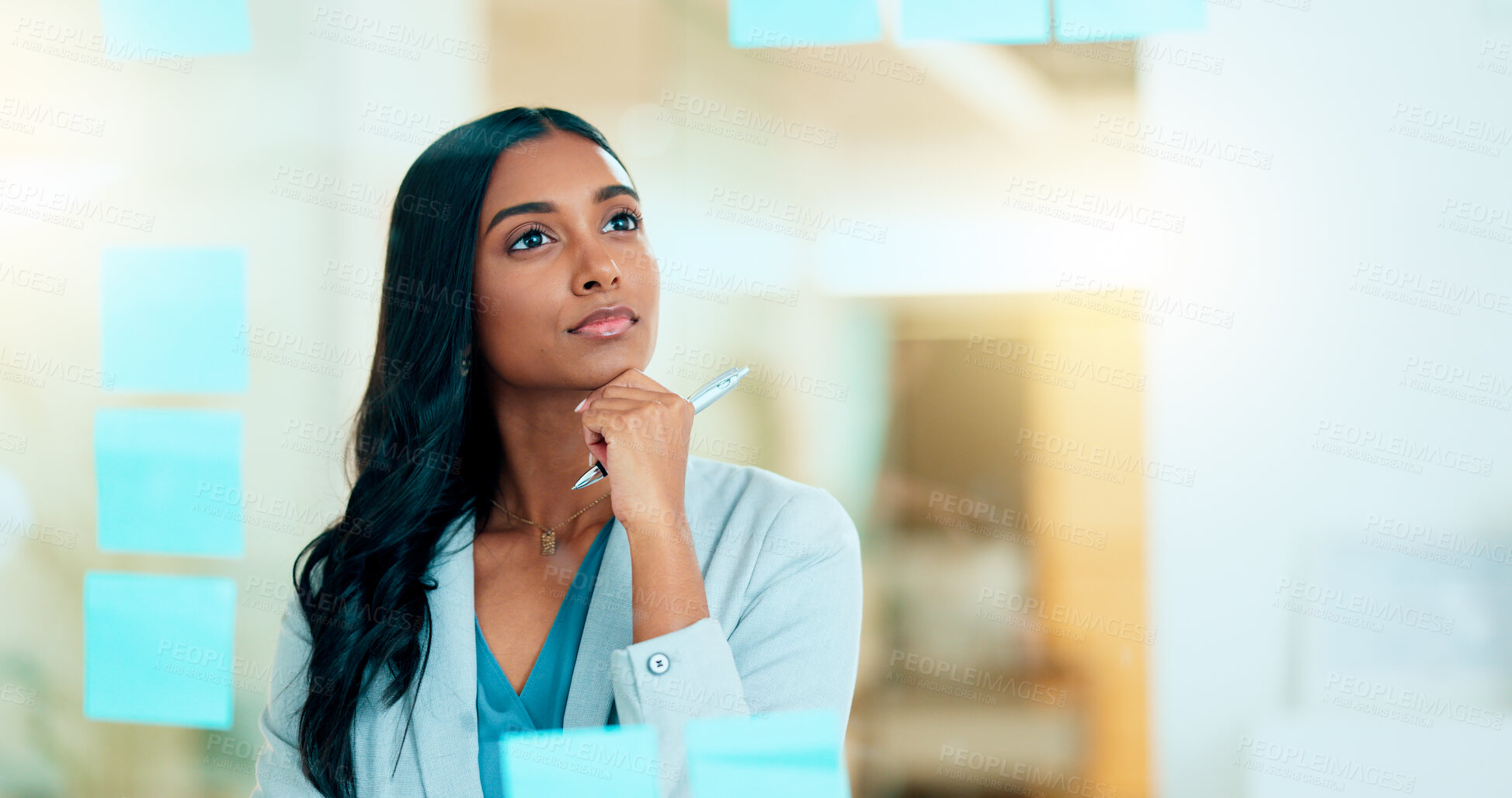 Buy stock photo Serious business woman brainstorm project ideas at a board with colorful sticky notes. Female marketing manager standing and writing business plan. Office worker thinking about corporate strategy.