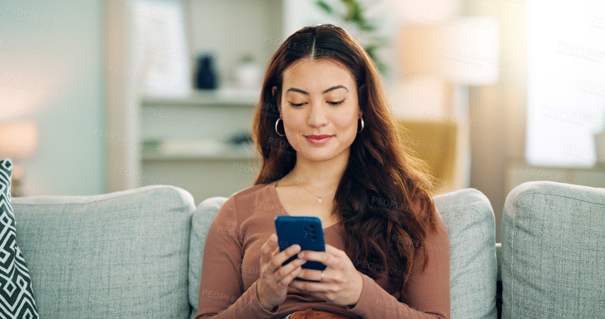 Buy stock photo Phone, social media and happy woman texting on a dating app and smiling on the weekend at home on the couch. Smile, chatting and young girl loves typing a message on a social networking website