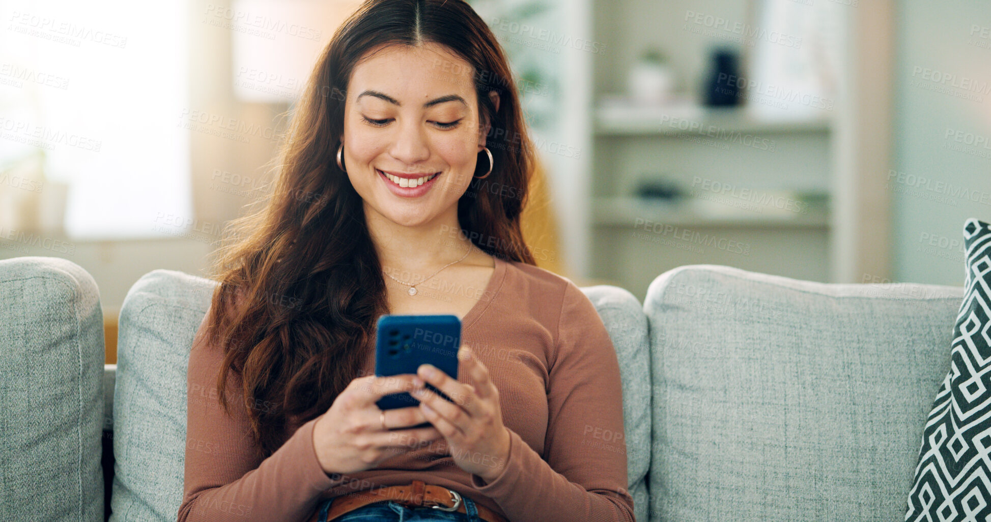 Buy stock photo Phone, social media and happy woman texting on a dating app and smiling on the weekend at home on the couch. Smile, chatting and young girl loves typing a message on a social networking website