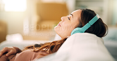 Relax, headphones and happy woman listening to music, radio or podcast while resting on sofa. Happiness, smile and calm girl from singapore sitting on the couch in living room at home with technology