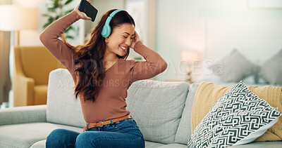 Phone, dancing and woman streaming music via headphones to relax with freedom on the weekend at home. Dance, excited and happy girl enjoys listening to a radio song or audio on an online subscription
