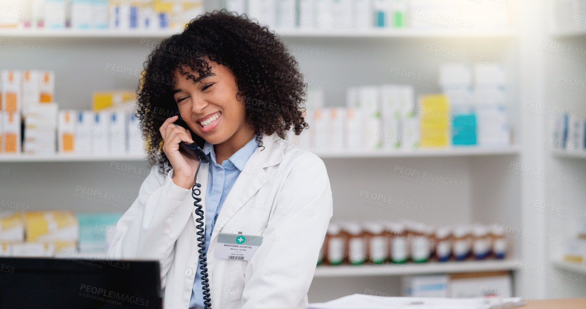 Buy stock photo Friendly pharmacist talking on the telephone and checking something on her computer in a pharmacy. Woman using pc to access drug database for inventory check or access customer's prescription online