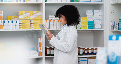 Buy stock photo Young and focused pharmacist use her tablet to do stock taking in a modern pharmacy drugstore. Multiethnic female health professional worker or medication expert in a chemist using a digital gadget
