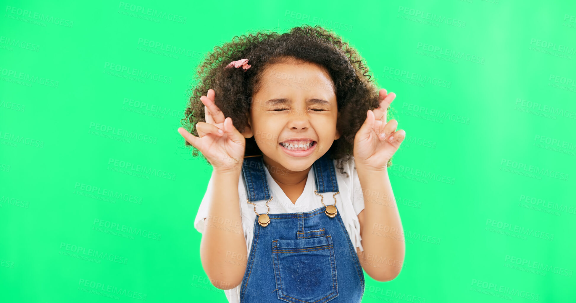 Buy stock photo Fingers crossed, wish and praying with girl in studio for good luck, hope and optimism. Excited, emoji and closed eyes with child isolated on green background for miracle, positive and youth