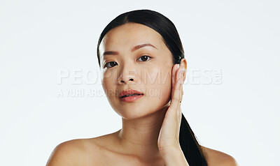 Skincare, asian woman and touch face in studio for beauty, dermatology or cosmetics on white background. Female model, portrait and facial aesthetic glow of shine, laser transformation and wellness