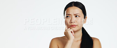 Skincare, thinking and Asian woman in a studio with a beauty, self care and natural routine. Question, doubtful and portrait of a female model with dermatology facial treatment by white background.