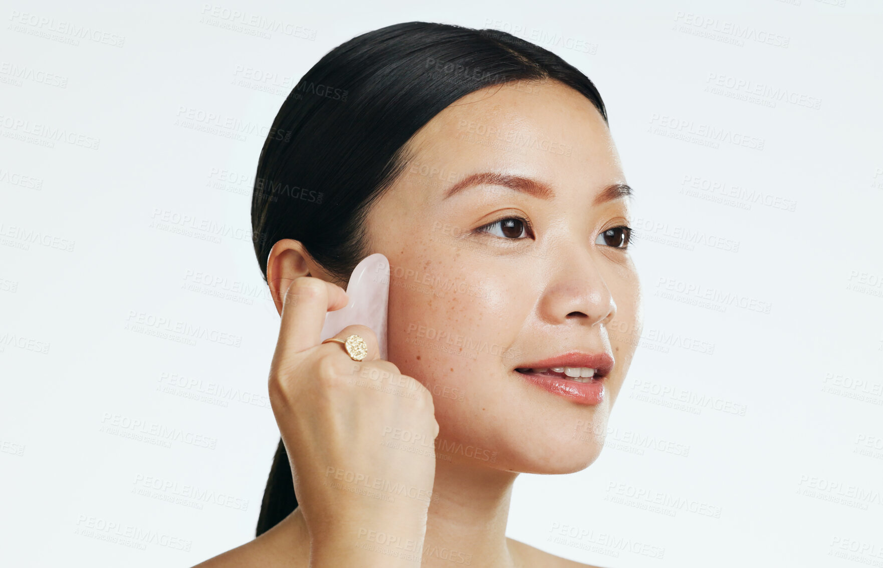 Buy stock photo Gua sha, beauty and woman massaging face isolated on a white background in a studio. Spa, skincare and an Asian girl with a product to massage for facial relaxation, treatment and anti aging