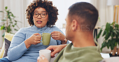 Interracial happy couple, conversation and coffee on sofa for morning bonding in living room together. Discussion, woman and man on couch with tea, quality time to relax, talk and plan day in lounge.