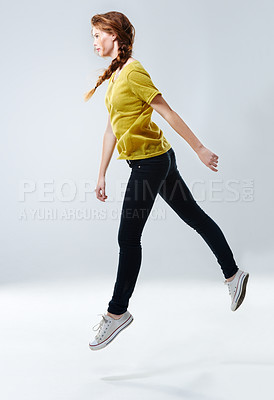 Buy stock photo Studio shot of a beautiful young woman in casualwear jumping against a gray background