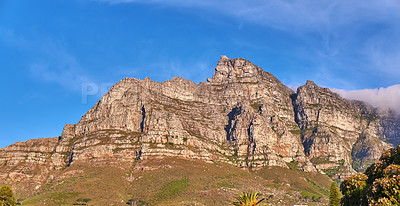 Buy stock photo Low angle view of Table Mountain against a bright blue sky. Rocky mountain peak in South Africa. Scenic landscape of a remote hiking location on a sunny day. Travel and explore nature on adventure