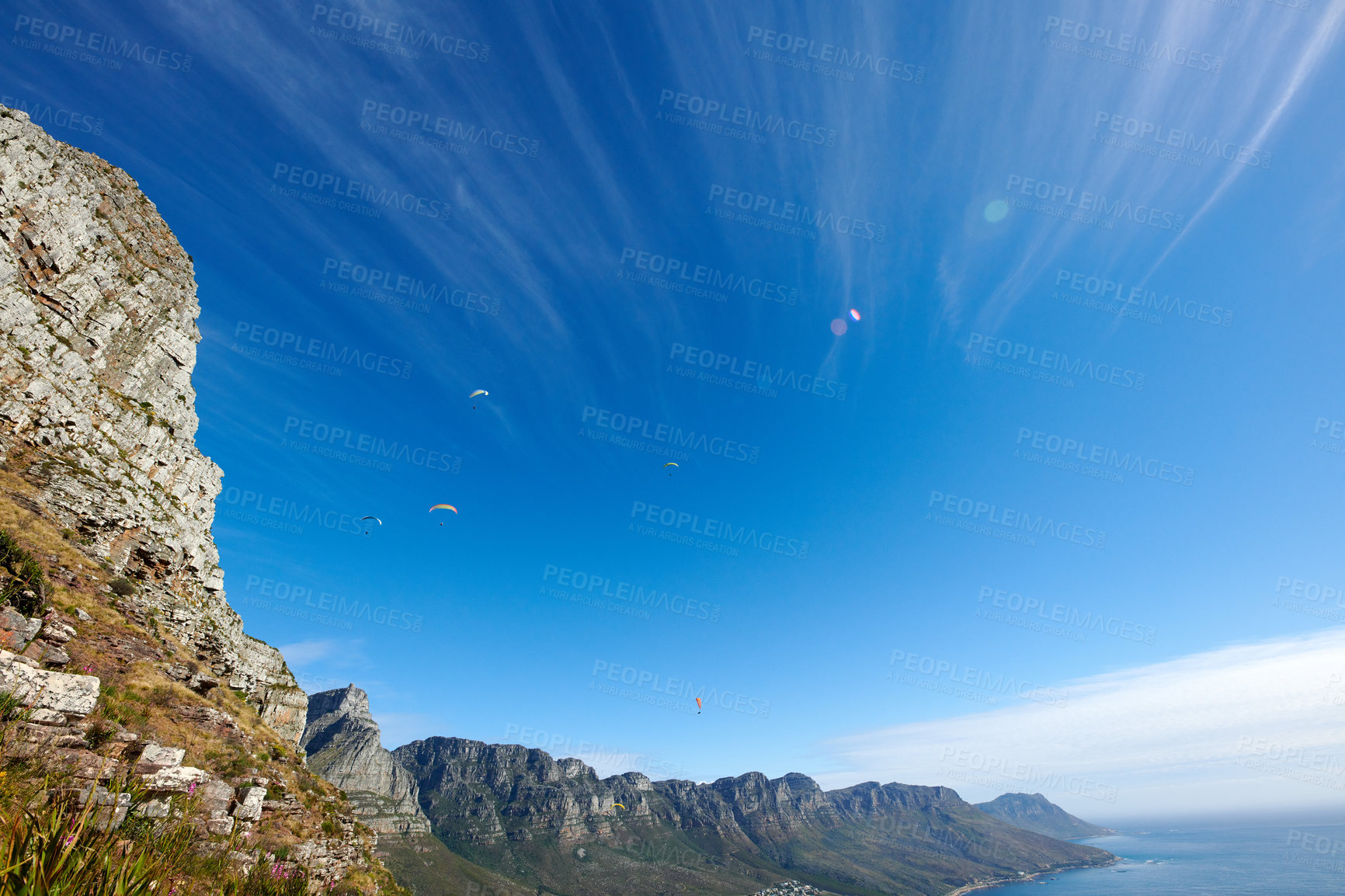 Buy stock photo Paragliding across the sky, flying high above the ocean and mountain. For an adrenaline filled summer of fun try an extreme sport with a view of nature. Adventure is for the daring and brave.