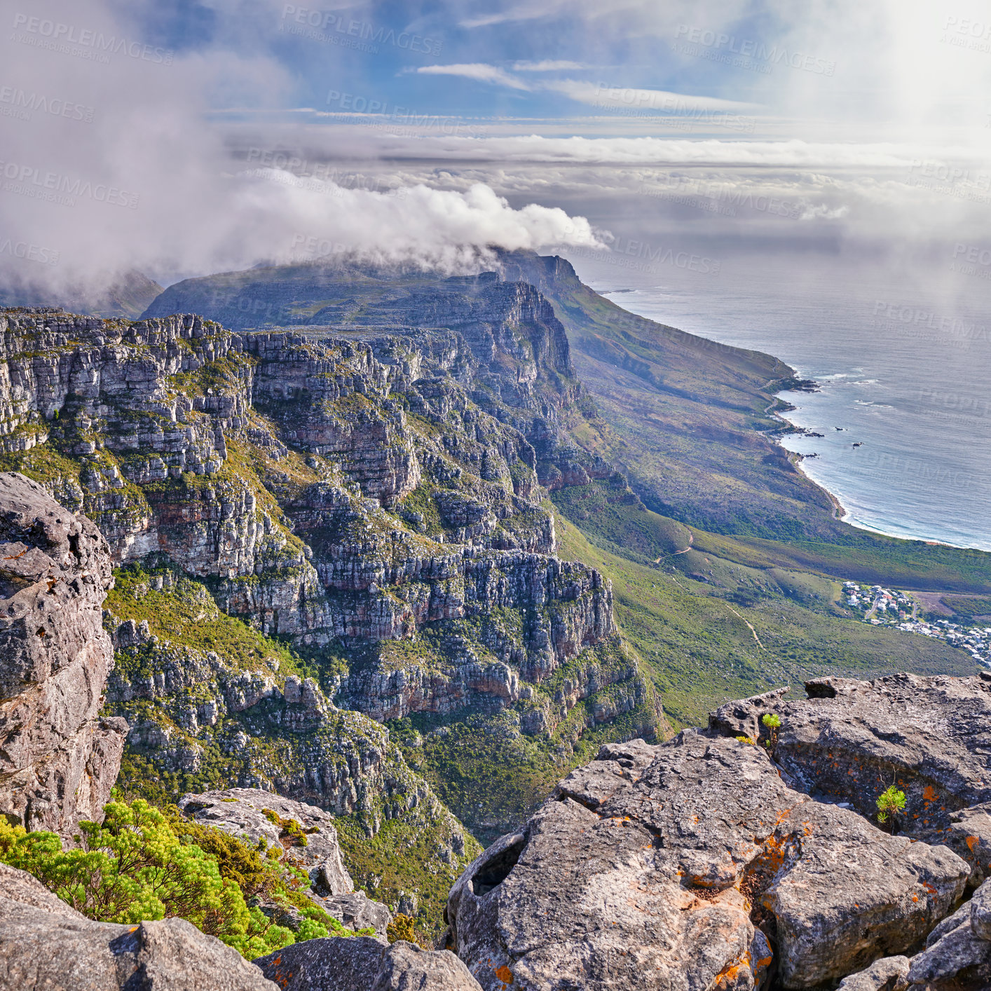 Buy stock photo Panoramic aerial nature views of clouds rolling over a mountain on the coast during summer. Copyspace scenic view of a natural environment on a coastline with rocks, plants, and greenery from above