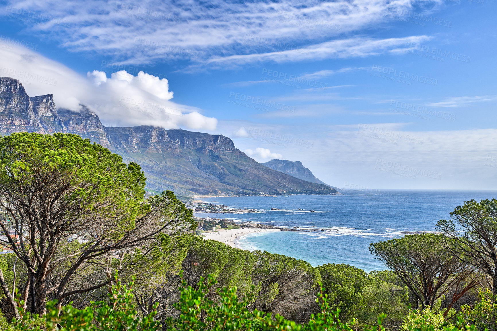 Buy stock photo The landscape of a mountain in the ocean surrounded by nature with a cloudy blue sky background. Beautiful view of the sea near bright green plants on a summer day. A scenic beach and peak in spring