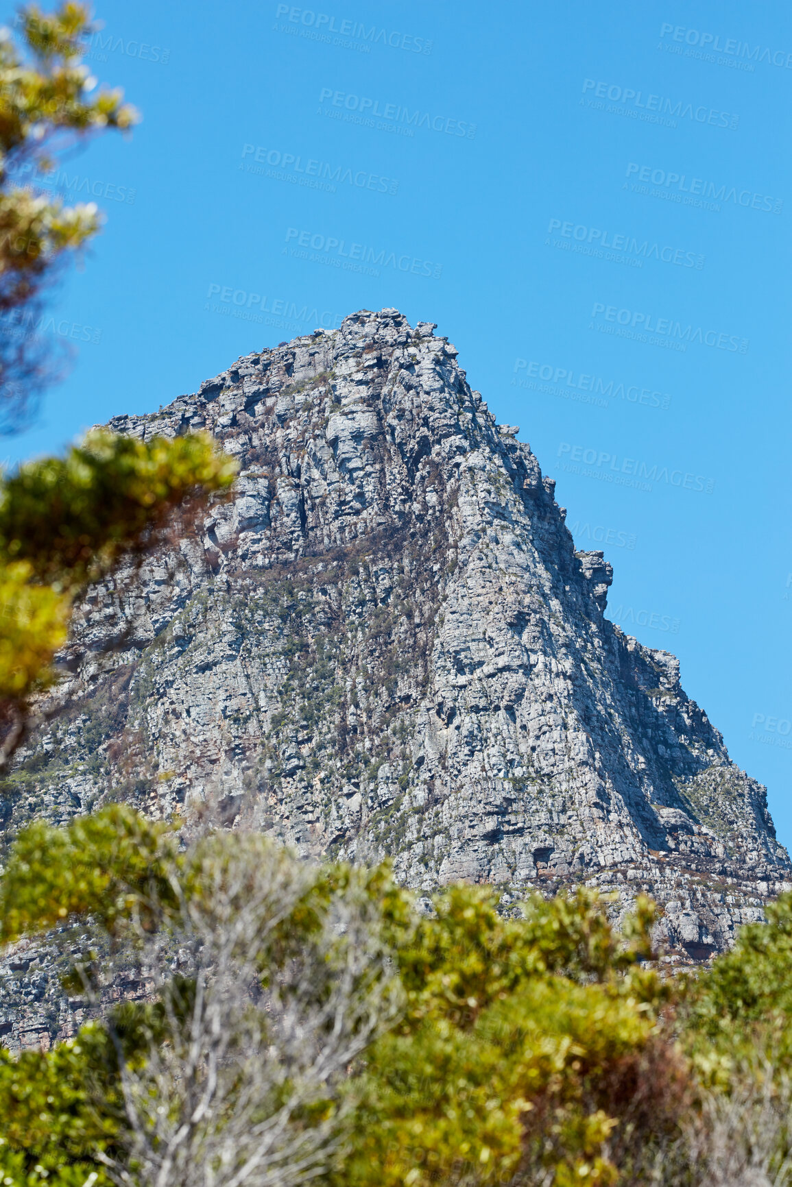 Buy stock photo A majestic mountain peak isolated against a clear blue sky with copy space from below. Scenic and quiet mountaintop or summit with a rocky landscape view of a remote location on a sunny summer day