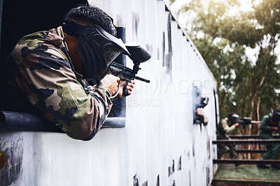 Aim, gun or people in a paintball shooting game with fast action on a fun battlefield on holiday. Man on mission, playing or player with military weapons gear for survival in an outdoor competition