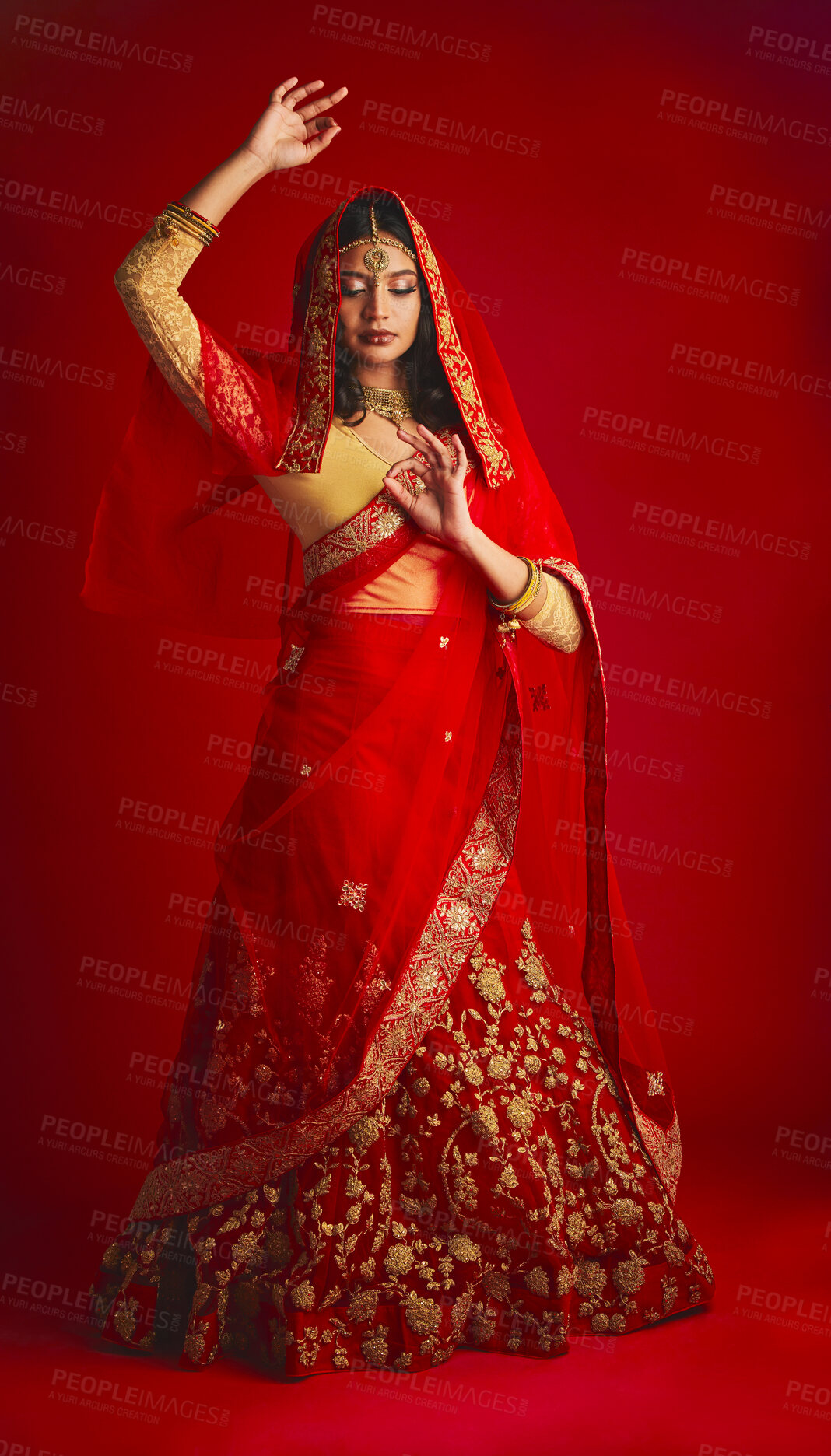 Buy stock photo Fashion, dance and Indian woman in a traditional dress, jewellery and celebration on a red studio background. Female person, girl and model with a cultural outfit, dancing and routine with confidence