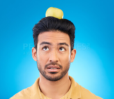 Buy stock photo Man, thinking or balance apple on head in studio isolated on a blue background. Confused, fruit or Asian person with food for healthy diet, nutrition or vitamin c for wellness, benefits or vegan idea