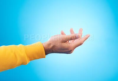 Buy stock photo Hands, giving and man in studio for charity, donation or help with reaching gesture against blue background. Palm, asking and male person with emoji for poverty, humanity and compassion, aid or hope