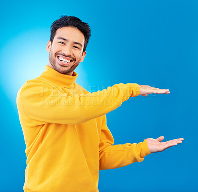 Buy stock photo Presenting, advertising and portrait of Asian man on blue background for news, showing and copy space. Studio, branding and face of male person with hand gesture for promotion, deal and presentation