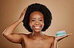Portrait, hair and keratin treatment with a black woman in studio on a brown background for cosmetics. Face, smile and haircare product in the palm of a happy female model for natural afro hairstyle