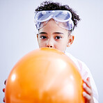 Portrait, science and a kid blowing a balloon in studio on a gray background for a childhood experiment. Children, education and laboratory with a female child wearing goggles while learning