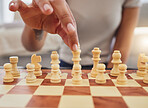 Chess, game and hand of woman with board moving piece for strategy, thinking and challenge. Competition, winning and zoom of hands of person with chessboard in living room for playing to checkmate