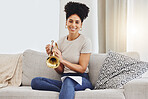 Portrait, woman and trumpet in home for music, learning and practice classic jazz song. Happy young female person, musician and brass horn instrument on sofa, living room and hobby of musical talent