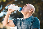 Man, drinking water and hydration for natural nutrition, sustainability or thirst in the nature outdoors. Tired and thirsty male person in fitness with healthy beverage for dehydration after exercise