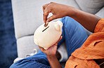 Woman, hands and coins in piggy bank for savings, finance or money investment on sofa at home. Hand of female person with piggybank for financial freedom, cash growth or budget planning at the house