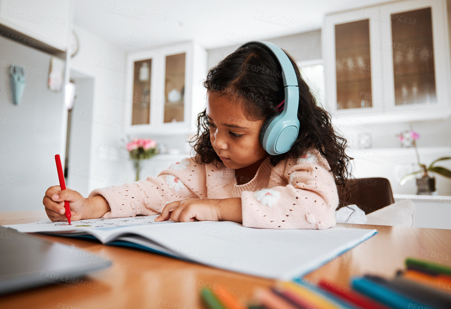 Buy stock photo Young child, learning and homeschool with headphones for homework, writing and drawing in books. Childhood development, focus and girl kid listening to audio while studying for kindergarten education