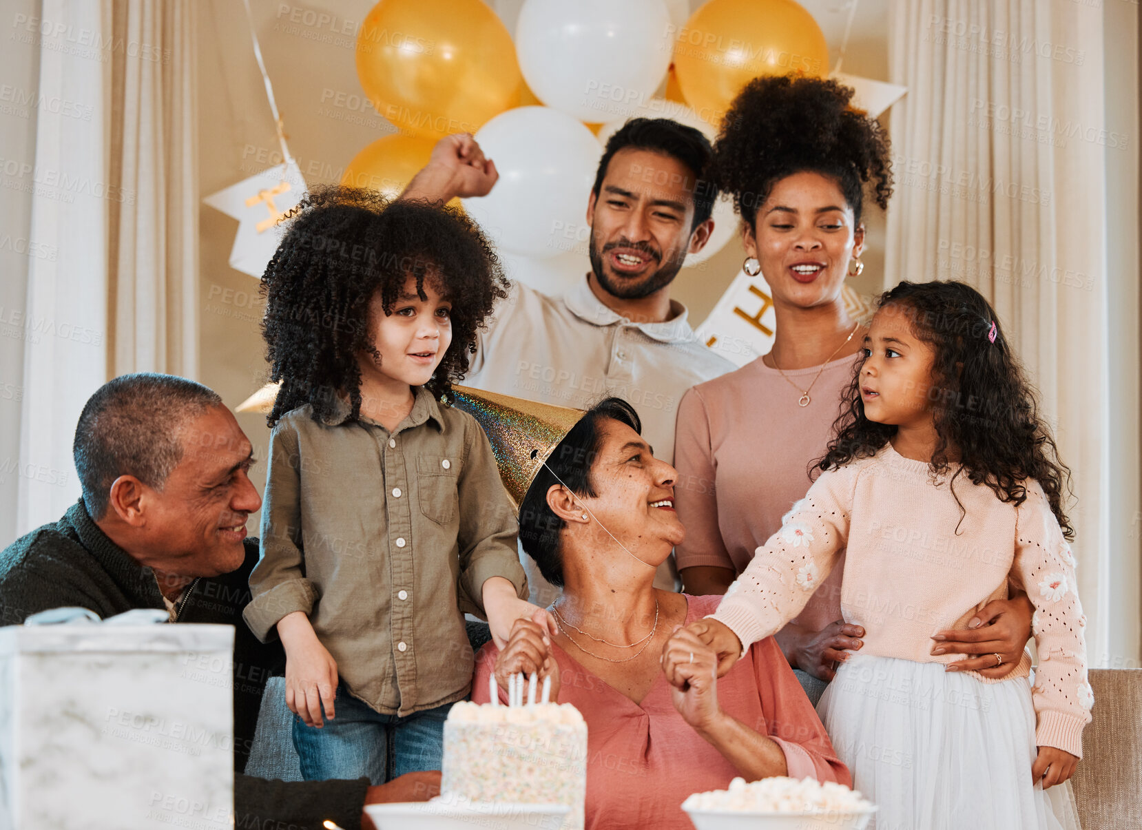 Buy stock photo Birthday, party and family with cake for grandmother in living room for event, celebration and social gathering. Happy, surprise and grandparents, parents and kids with dessert, snacks and presents