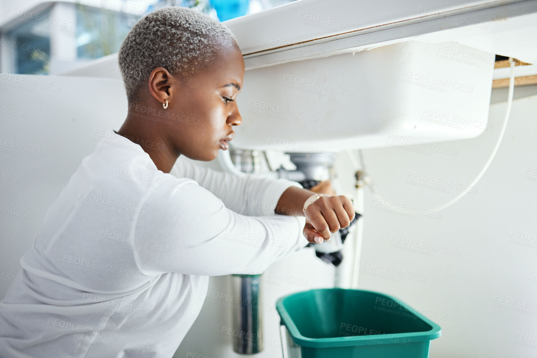 Buy stock photo Plumbing, leak and time with a black woman in the bathroom of her home waiting for repair assistance. Sink, emergency and watch with a young female homeowner in her house to stop water using a bucket