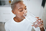 Health, glass and woman drinking water for hydration, wellness and liquid nutrition at her home. Thirsty, energy and African female person enjoying cold healthy drink in the kitchen of her apartment.