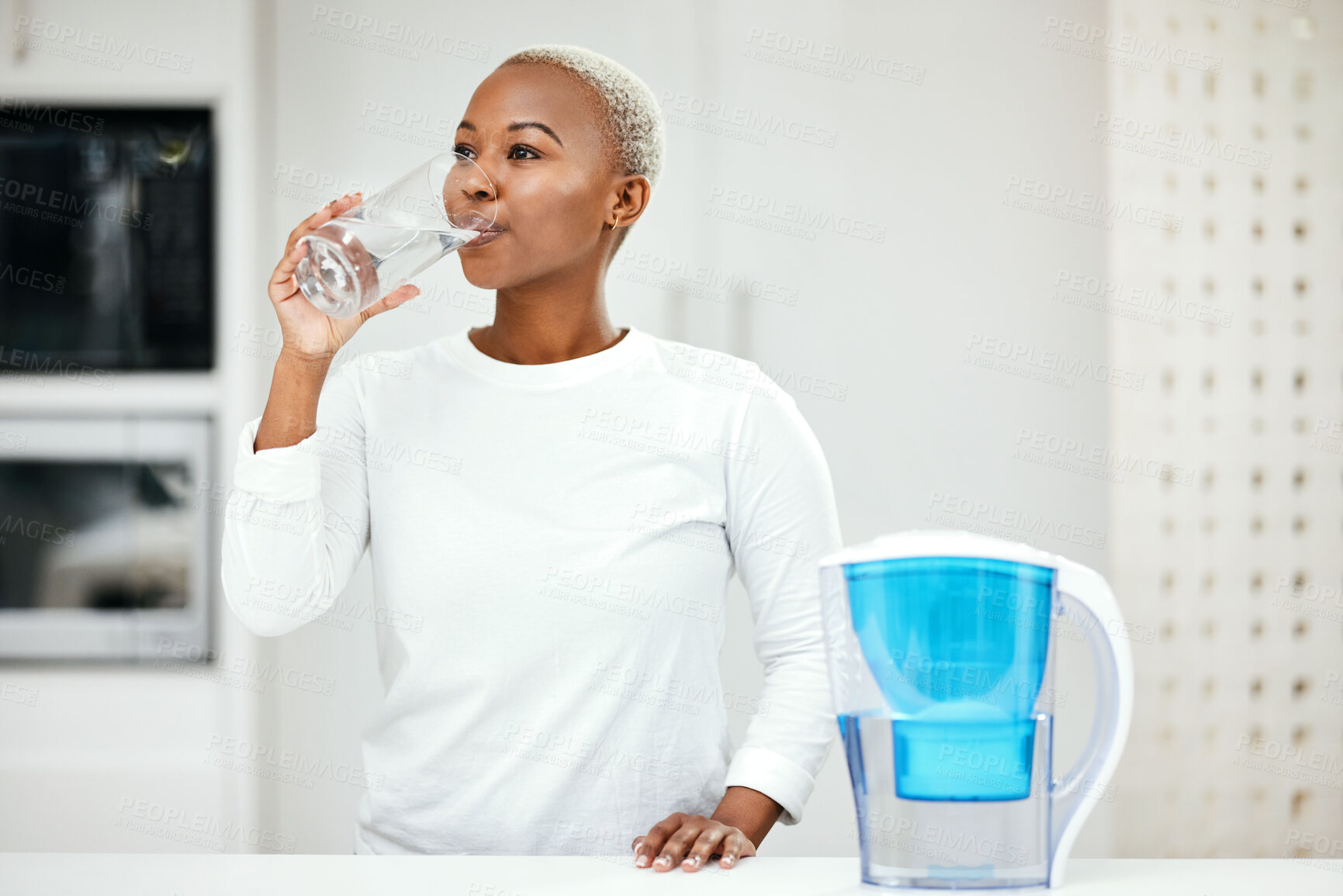 Buy stock photo Woman, filter and drinking water for health at home for a healthy lifestyle, diet and nutrition. Young african person with a glass from a container or pitcher in a kitchen for detox and wellness  