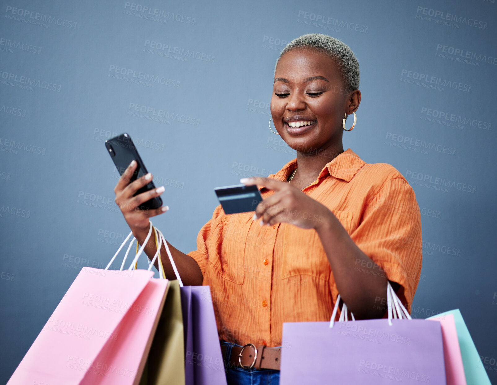 Buy stock photo Bags, retail and black woman with a credit card, smartphone or ecommerce on a grey studio background. Female person, shopper or model with cellphone, boutique items or purchase with shopping or smile