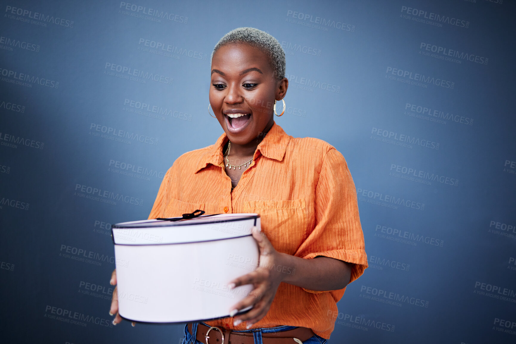 Buy stock photo Black woman, present package and surprise in studio with excited smile, birthday and blue background. African girl, happy and wow with box, gift and fashion for celebration, winner and birthday party