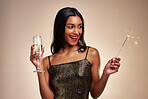 Happy woman, sparkler and celebration with party, Champagne and new year on studio background. Fireworks, alcohol drink in glass and holiday fun, luxury event and excited female person with sparks