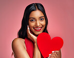 Portrait, heart and romance with a woman on a pink background in studio for love or affection. Smile, emoji and social media with a happy young female holding a shape or symbol on valentines day