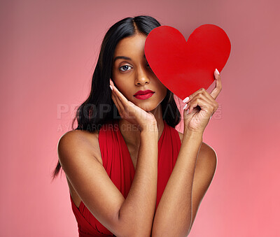 Buy stock photo Woman, paper heart and face in studio portrait for makeup, beauty or romantic sign by red background. Girl, fashion model and cardboard emoji with love for cosmetic, valentines day date and aesthetic