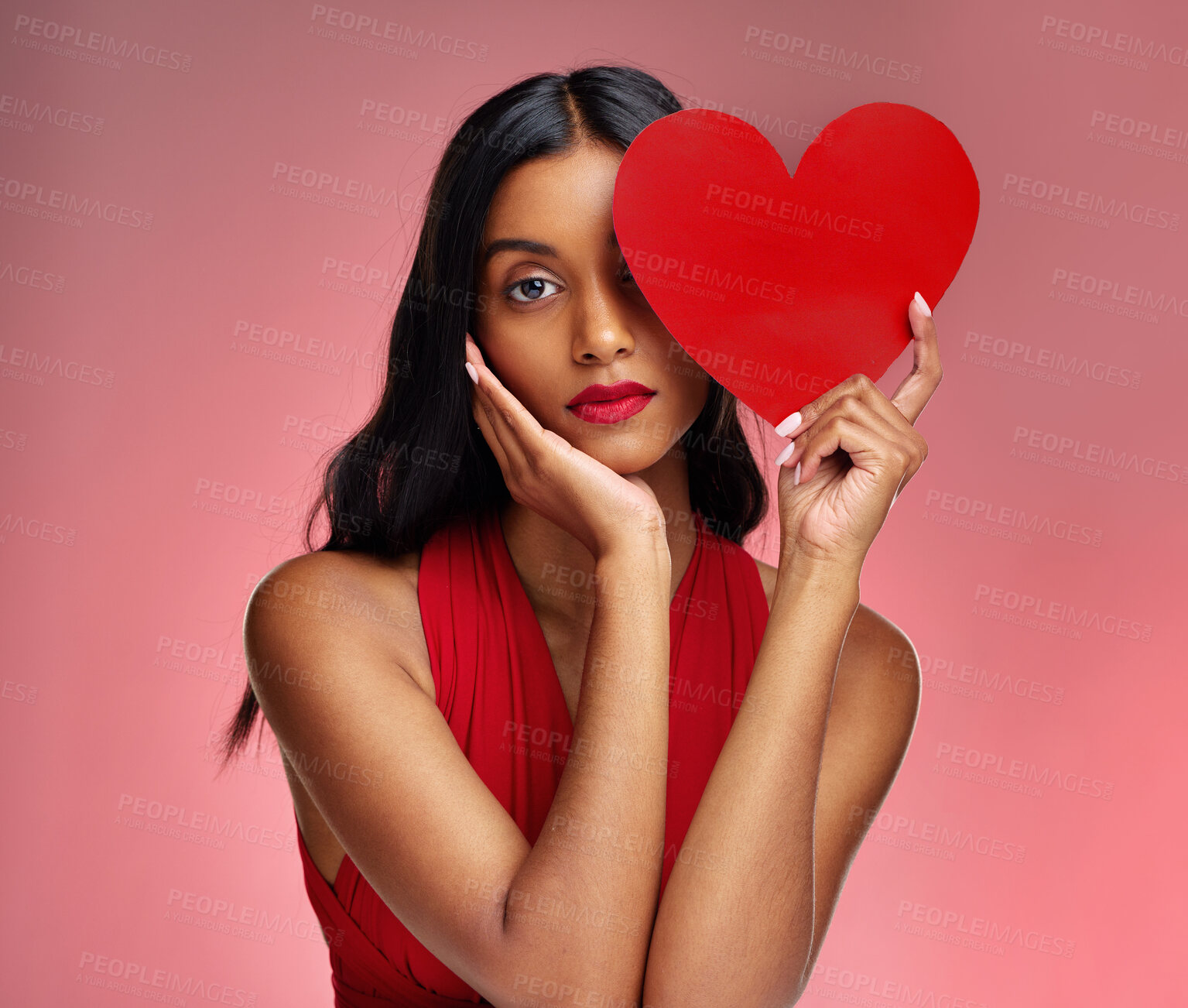 Buy stock photo Woman, paper heart and face in studio portrait for makeup, beauty or romantic sign by red background. Girl, fashion model and cardboard emoji with love for cosmetic, valentines day date and aesthetic